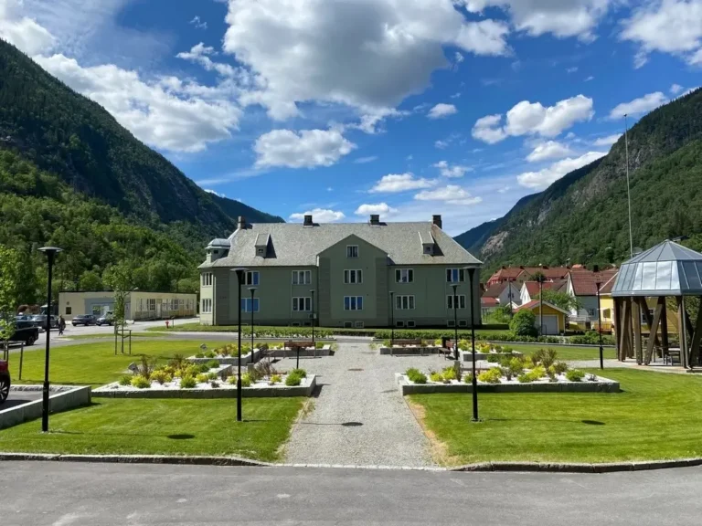 Grøntområde på utsiden av Mandheimen. Gress og opphøyde bed i naturstein.